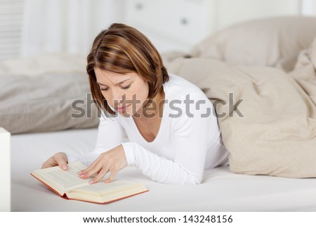 Image of a woman relaxing and reading a book in bed.