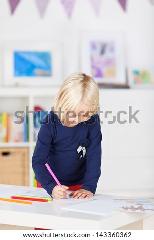 Concentrated little girl drawing on paper at table