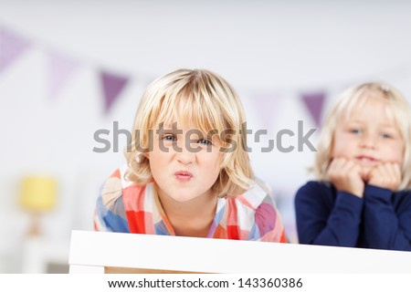 Portrait of little girl puckering lips while leaning on table