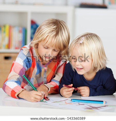 Two Concentrated little girls drawing on paper at table