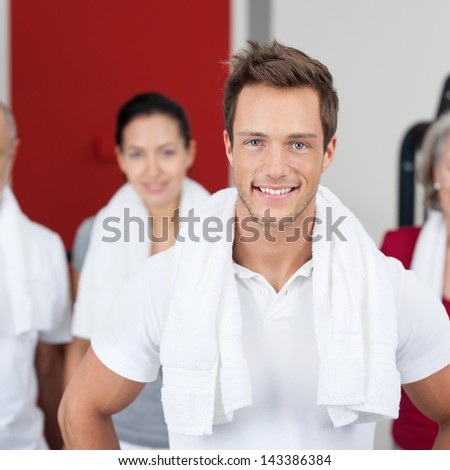Portrait of young man smiling with group in gym