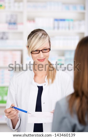 Female pharmacist talks to patient about the medical prescription inside the pharmacy