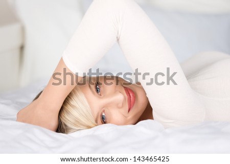 Attractive woman posing with hands on her head in bedroom