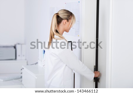 Beautiful young doctor opening the door in the lab