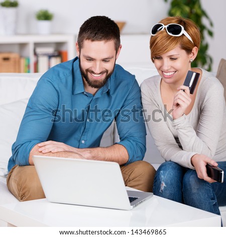 Portrait Of Happy Couple Shopping Online With Credit Card In House