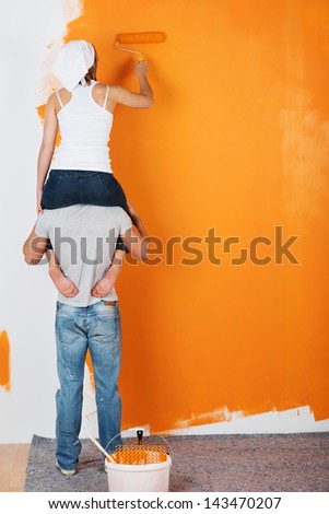 Young Couple Is Having Fun Painting A Wall