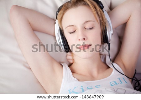 Sleeping woman lying on bed while listening music through headphone