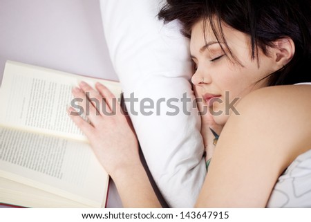 Cheerful woman falling asleep while reading book in a close up shot
