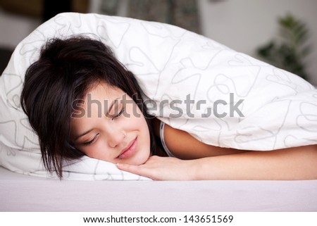 Smiling beautiful female fall asleep in bed with white linen