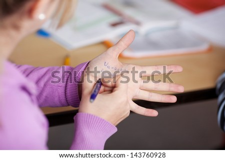 Schoolgirl writing on her hand for cheating in the class tests.