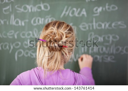 Female student during Spanish class in front of a blackboard with pen in hair