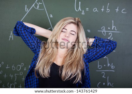 Relaxed student in class is stretching in front of blackboard