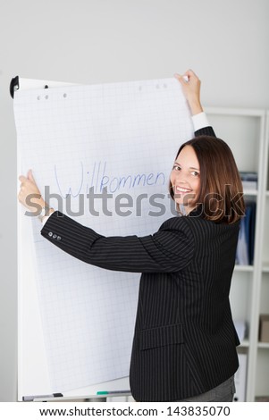 Portrait of happy businesswoman holding welcome sign in office