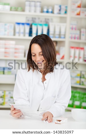 Mid adult female pharmacist reading prescription paper in pharmacy