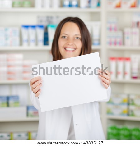 Portrait of mid adult female pharmacist holding blank paper at pharmacy