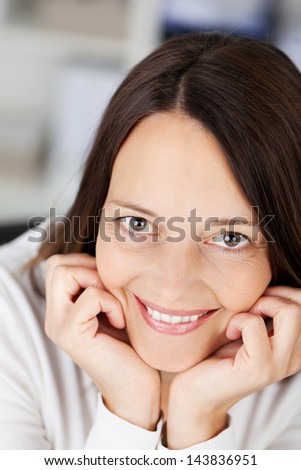 Close up portrait of smiling female with hands on her chin