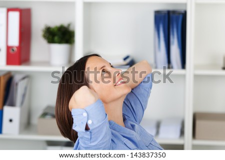 Happy relaxed businesswoman with hands behind head looking up in office
