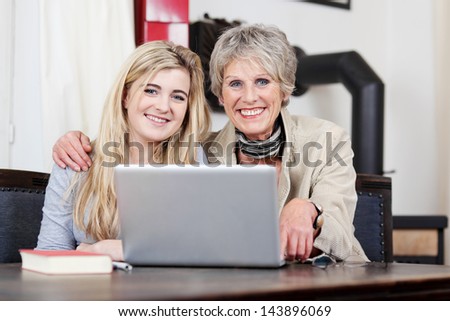 Portrait of a smiling grandmother and granddaughter using laptop at home