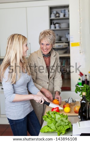 Smiling grandma and granddaughter cutting vegetables in the kitchen