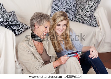 Smiling grandma and granddaughter looking at photos in the living room