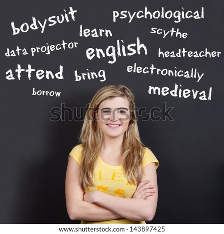 Portrait of a confident smiling teenage girl with arms crossed against English vocabulary on black background