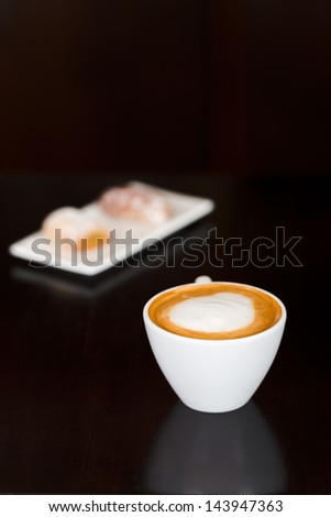 Closeup of cappuccino and sweet food in plate on cafe table