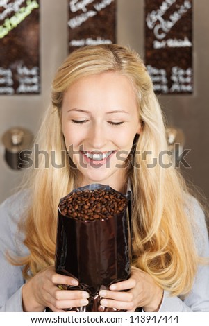 smiling blond woman holding package of coffee beans