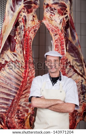 confident smiling butcher standing in cold room
