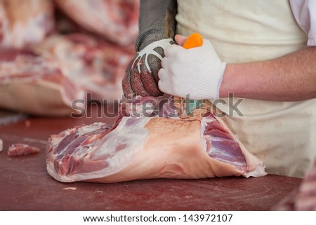 Closeup of male butcher\'s hands cutting meat with knife in shop