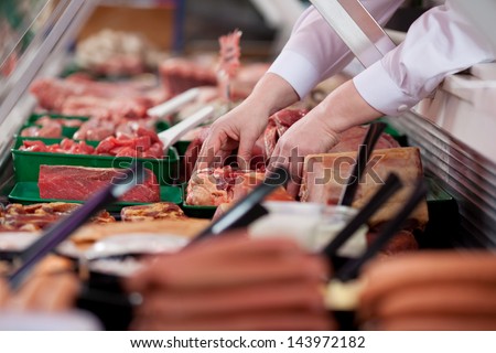 Closeup Of Butcher\'S Hands Arranging Meat In Display Cabinet At Shop