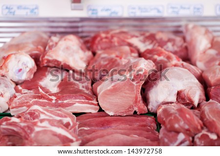 Selection of different cuts of fresh meat on display in a butchery in a refrigerated counter