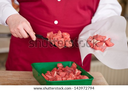 Midsection of butcher packing meat pieces in paper at shop