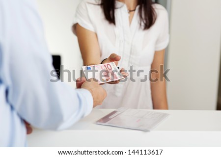 Cropped image of patient paying money to receptionist in dentist clinic