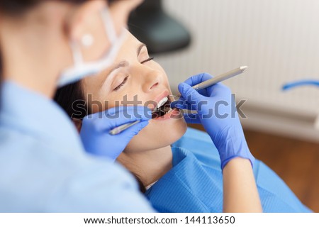 Closeup Of Female Dentist Examining Mid Adult Patient\'S Mouth In Clinic