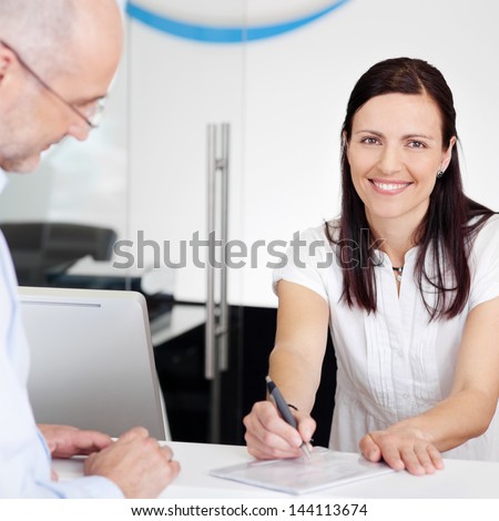 Portrait of female receptionist explaining form to patient in dentist clinic