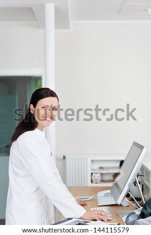 Portrait of confident mid adult receptionist at reception counter in dentist\'s clinic
