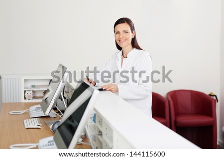 Smiling female doctor standing at the reception desk