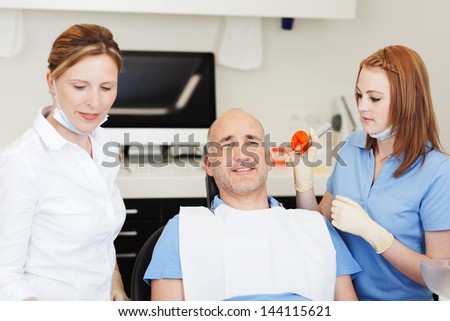 Female dentists starting examining patients mouth with tools in clinic
