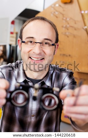 confident optician holding test lenses in a shop