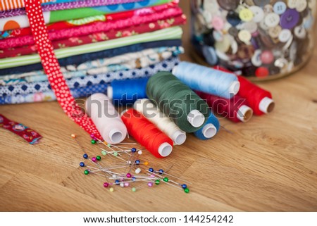 Needlework and handicraft concept with bright colorful fabric, thread, pins and buttons displayed on a wooden counter