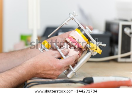 Closeup of dental technician\'s hands working with articulator in dental laboratory