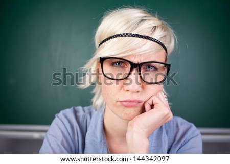 Closeup portrait of a blond woman contorting her face against chalkboard