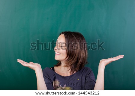 Closeup of mid adult woman displaying invisible product against chalkboard
