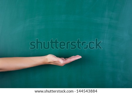 Arm and hand in front of a blackboard