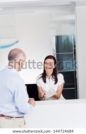Portrait of female receptionist explaining form to patient in dentist clinic