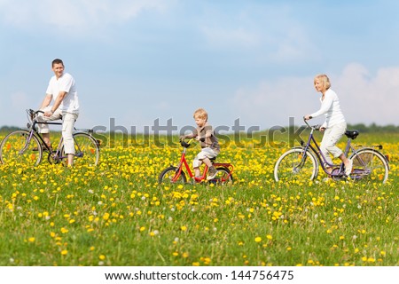 happy family cycling through green fields with flowers