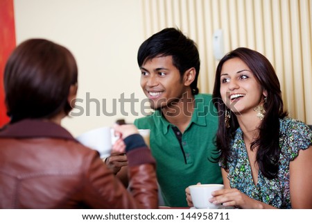 Happy couple at a cafe talking with friends