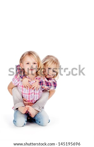 Portrait of cute blond little girl giving piggyback ride to sister isolated over white background