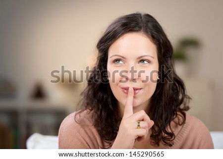 Closeup of young woman with finger on lips at home