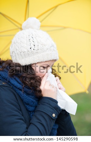 Young woman in winter clothes suffering from cold at park